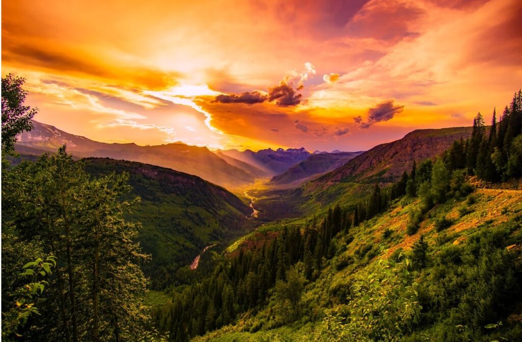 A lush green mountainous landscape with a soul warming purple and orange fusion of light.